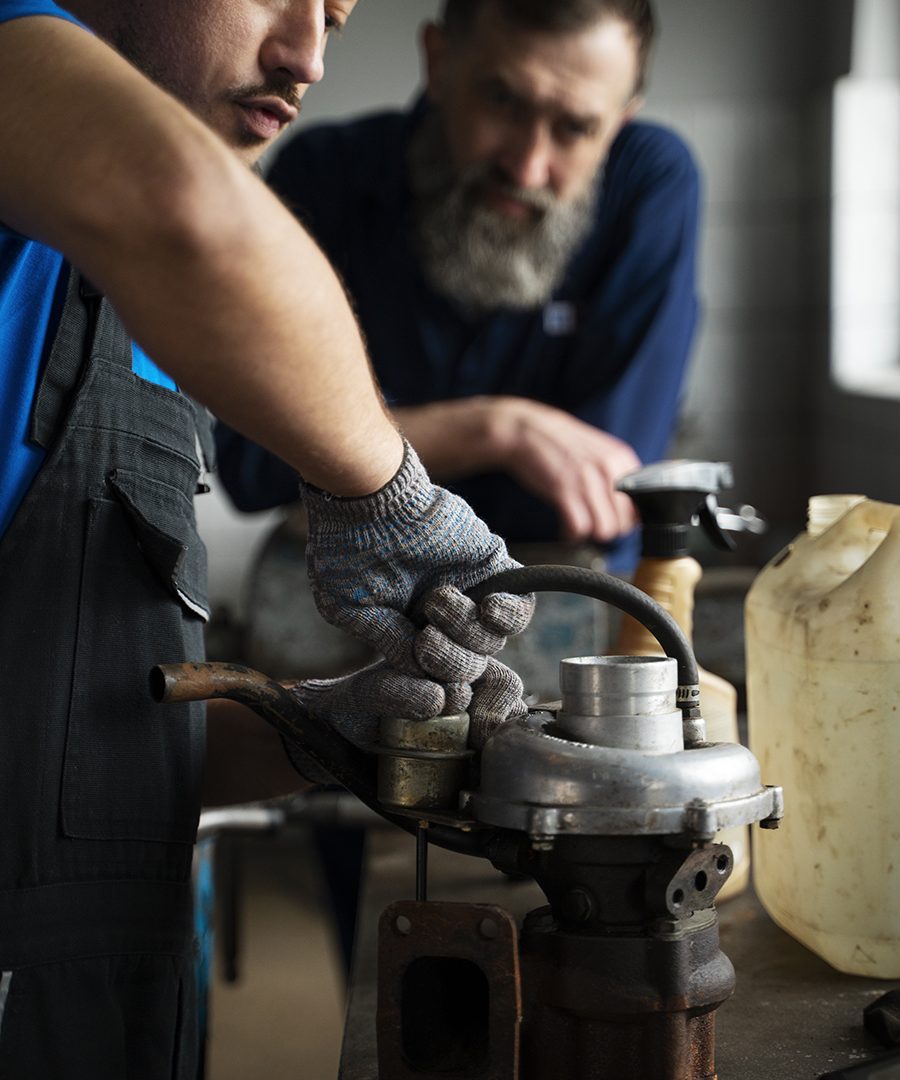 male-mechanics-working-car-shop-together